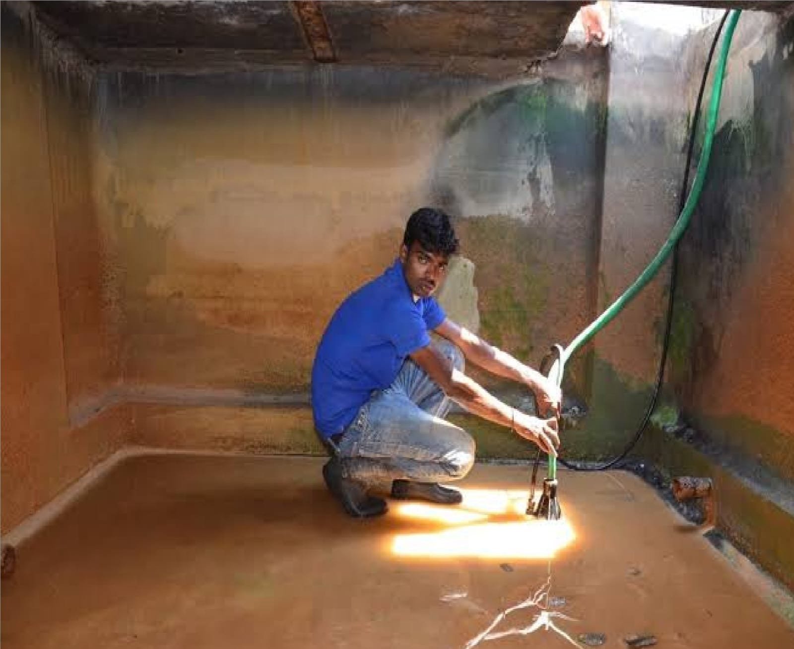 Technician brushing the floor of an underground water tank
